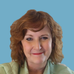 A woman with curly brown hair smiles at the camera, wearing a light green shirt against a blue background.